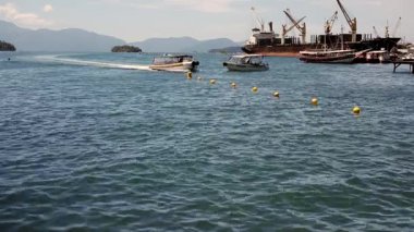 Angra dos Reis, Brezilya. 14 Ocak 2026: Angra dos Reis limanında turist botu manevrası. Sahildeki yaşamı, tekneleri ve arka planda dağlar ve Atlantik ormanı olan manzaralı marinayı yakalar.