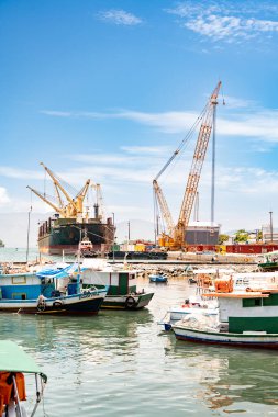 Angra dos Reis, Brezilya 14 Ocak 2026: Angra dos Reis 'teki konteynır terminaline küçük renkli balıkçı tekneleri üzerinden bir konteynır, konteynırlar ve uzun bir vinçle bakın.