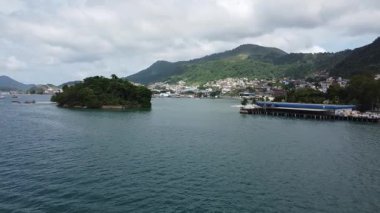 Brezilya 'nın Ilha do Coqueiro ve Angra dos Reis adalarına yaklaşan hava çekimi. Kasaba merkezi ve çevre ormanlarla kaplı dağların yanı sıra kıyı tesisleri de arka planda yer alıyor.