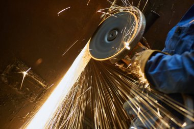 Öğütme makinesi olan ağır endüstri işçilerinin yakın çekimi kıvılcım saçıyor.