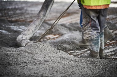 İnşaat işçileri bir pompa kamyonundan beton dökerek inşaat demiri olan bir temele beton dökerek bir bina için sağlam bir temel oluşturuyorlar.