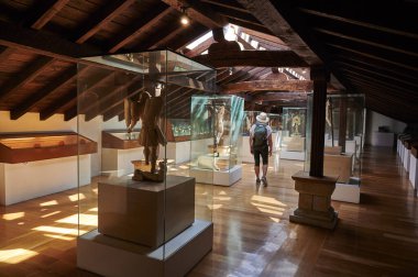 08-28-2021, İspanya 'daki Museo Diocesano Regina Coeli, Santillana del Mar, Cantabria, İspanya' daki müzede hasır şapkalı ve sırt çantalı kadın.