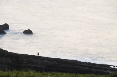 Cantabrian kıyılarındaki kayalıklarda gün batımında balıkçılar