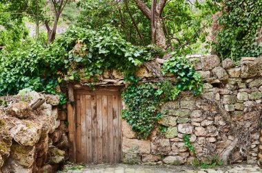 Taş duvar ve eski ahşap kapı özel tarlaya açılıyor.