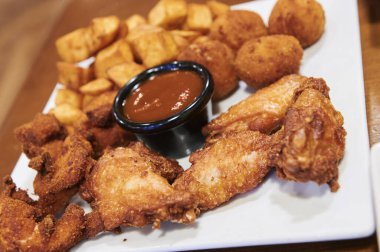 Kızarmış tavuk, kroket ve barbekü soslu patates kombinasyonu.