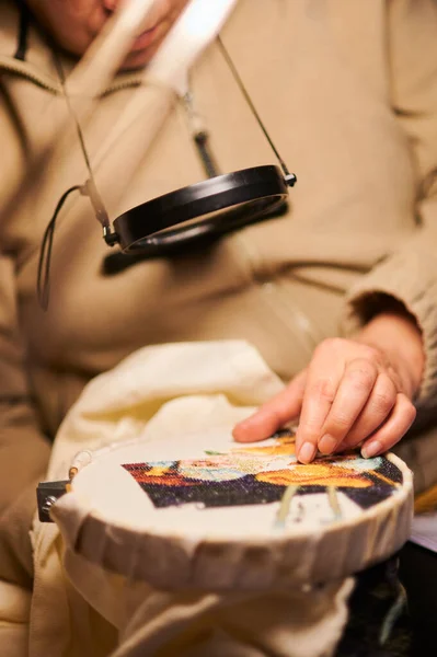 Kadın elleri çapraz dikiş yapıyor. Kapalı bir nakış..