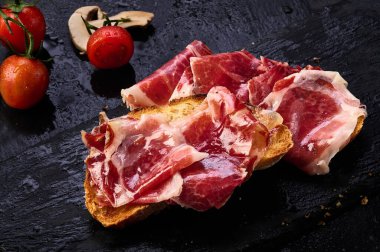 Bir dilim kızarmış ekmeğin üzerinde İber jambonu dilimleri