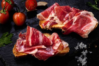 Bir dilim kızarmış ekmeğin üzerinde İber jambonu dilimleri