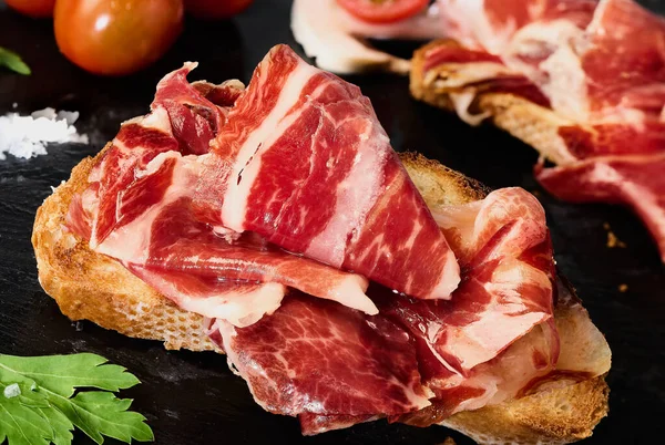 Bir dilim kızarmış ekmeğin üzerinde İber jambonu dilimleri