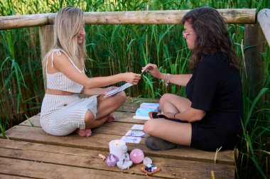 Bütünsel kartlarla oynayan iki genç kadın, bütünsel terapi.