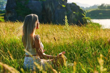 Sarışın kız şafakta meditasyon yapıyor.