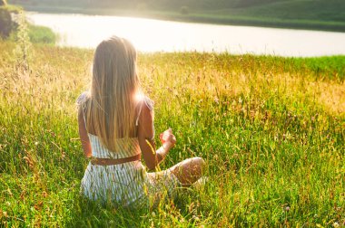 Sarışın kız şafakta meditasyon yapıyor.