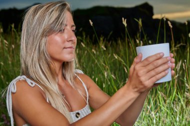 Gün batımında meditasyon yapan sarışın kızın portresi.