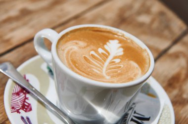 Yüzeyinde çiçek resmi olan beyaz fincanlı kahve.