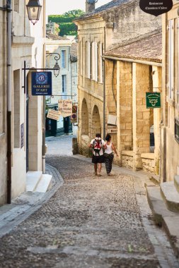 Geleneksel taş mimarisi ve Avrupa köyündeki tarihi binalarla çevrili, eski ve büyüleyici bir kasaba caddesini keşfeden bir çift.