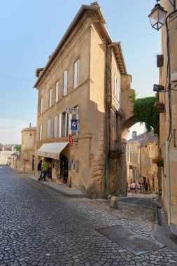 Cobblestone sokağı antik aziz Emilion köyünde kıvrılarak geleneksel bir kafe ve sarmaşık kaplı bir kemer yolu gösteriyor.