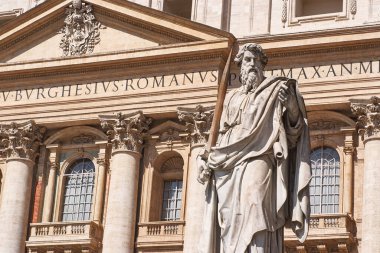 Aziz Paul Havarisi elinde bir kılıç, şehitliğinin bir sembolü, antik bir binanın önünde yazıtlarla duruyor.