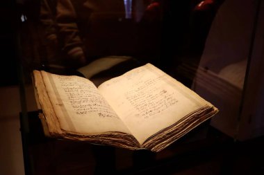 Hollanda 'daki Rembrandt House Museum' da eski açık bir kitap sergilenmektedir. Sayfalar hassas ayrıntıları gösteriyor, tarihi el yazmalarının özünü yakalıyor. Sahne müzede muhafaza edilen zengin kültürel ve sanatsal mirası yansıtıyor.