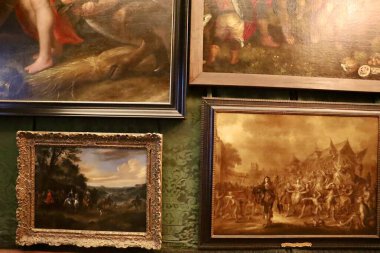 Fotoğrafta Hollanda 'daki Het Loo Sarayı' nda sergilenen resimler var. Bir sanat eseri manzarayı resmederken, diğeri klasik temaları ve asil zevkleri yansıtan insan figürleri sunuyor..