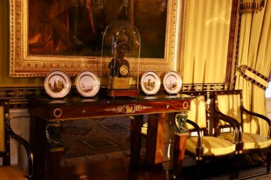 Büyük resim dekoratif masanın üstündeki duvara hükmediyor. Seramik plakalar ve cam kaplı büstler tarihi içeriyi zenginleştiriyor.