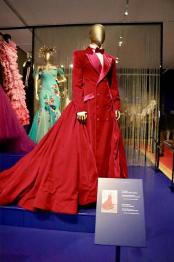 Sahne kostüm tasarımının çarpıcı bir örneği olarak gösterilen uzun kırmızı bir tiyatro elbisesi.