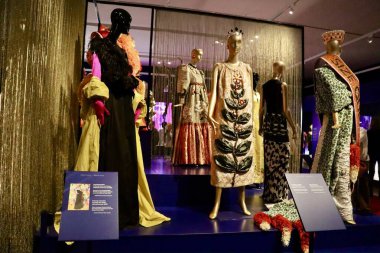 Fotoğrafta, altın ve bej tonlarında sahne kostümleri giymiş bir grup manken yer alıyor. Zengin dokular ve parıldayan kumaşlar performans odaklı karakterlerini vurguluyor.
