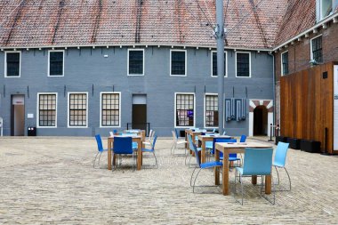 Mavi duvarı ve açık masaları olan müze avlusu.