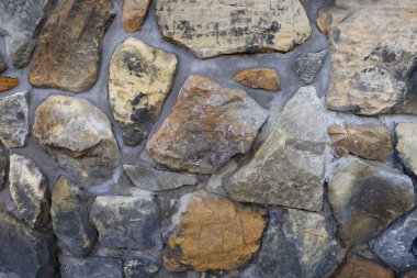 Doğal kaba yüzeyli, nötr fotoğraf arkaplanı olarak kullanılan dokulu taş bir duvar..
