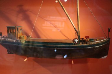 Ayrıntılı ahşap model gemi kırmızı zemin üzerinde sergileniyor. Tarihi deniz teknesini temsil eden el yapımı minyatür..