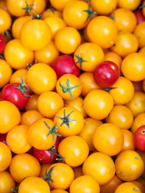 Taze vişneli domateslerin üst görüntüsü yoğun bir şekilde paketlenmiş, tüm çerçeveyi dolduruyor. Kırmızı ve sarı karışımı. Yemek arkaplanı ya da doku için mükemmel.