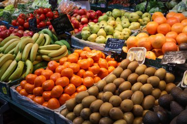 Pazar tezgahlarında muz, mandalina, kivi, armut, elma ve domatesler de dahil olmak üzere çeşitli taze meyveler.. 