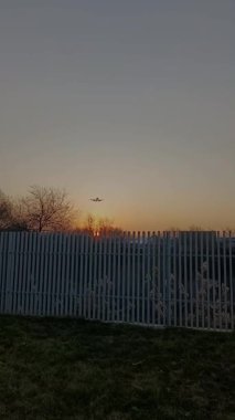 Gün batımından çıkıp doğrudan kameraya doğru uçan bir uçak. Uçak üstümüzden geçiyor ve iniş için iniyor, dramatik ve sinematik bir hava sahnesi yaratıyor.. 