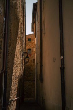 Taş binalar, derin gölgeler ve duvar fenerinin sıcak gölgeleri arasındaki dar sokaklar, samimi geçitler.