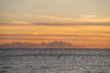 Huzurlu Okyanus 'un üzerinde bulutlu yumuşak bir gün doğumu sakin bir sabah güneşi yansıtan sakin sular üzerinde dinlendirici bir gün ışığı Yumuşak bir bulutun altında sessiz bir okyanusu aydınlatan gökyüzü.