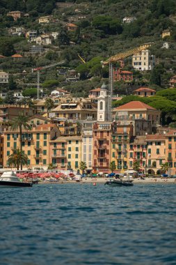 Rıhtımın tepesinde çan kulesi olan renkli binalar rıhtımda dizili küçük tekneler.