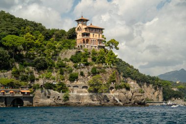 Süslü tepedeki villa turkuaz denizi, teraslı bahçeler ve kemerli balkonlar yamaçtan aşağı dökülüyor.,