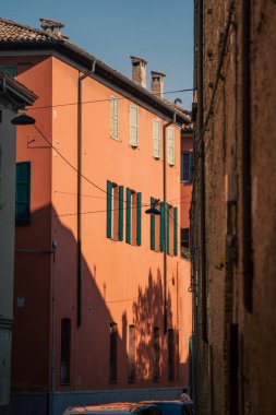 Parlak turuncu arka plan gölgeler ve kepenkler, canlı turuncu duvar belirgin ağaç gölgeleri ve pencere desenleri ve zıt aydınlatma