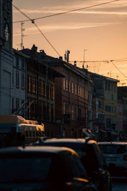 Alacakaranlık bulvarı araba ve banliyö ile dolu, zıtlaşan gökyüzü, araba ışıkları şeritler oluşturan, şehir yoğunluğu ve hareket, eve giden banliyö, dinamik katmanlı