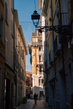 Güneş ışığıyla yıkanmış canlı şehir yolu. Uzak saat kulesi, güneşli şehir yaya koridoru. Arka planda antika mağazalar ve önde gelen saat kulesi var.