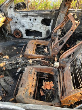 Arabanın içi yanmış koltuklar, gösterge paneli ve paneller görünüyor.