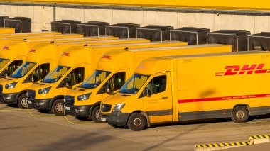 Alman posta servisinin sarı elektrik dağıtım araçları Almanya 'nın Waiblingen (Stuttgart tarafından) lojistik merkezinde 26.12.2025' te şarj ediliyor. Paket taşıma işlemlerinin dikey görünümü, modern lojistikte elektrikli araçların kullanımı