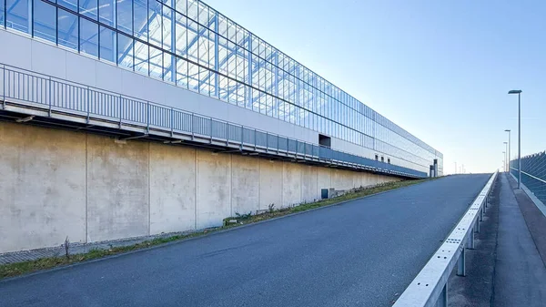 Dış cepheye bağlı metal bir merdiven bulunan sanayi deposu. Yapı beton duvarlar ve büyük cam yüzeyler, modern endüstriyel mimari, teknik altyapı ve lojistikle ilgili tesisleri birleştiriyor.