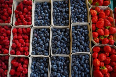Yerel bir marketteki geri dönüşümlü kağıt tepsilerde taze yaban mersini, çilek ve ahududu. Sağlıklı taze yiyecek.