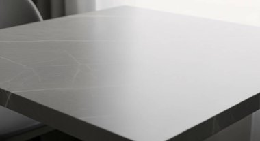 Yumuşak ışıklandırma ve gri arkaplanlı, minimalist tasarım ve modern çalışma alanı estetiğini vurgulayan temiz beyaz bir masa köşesi.