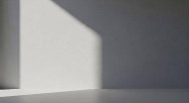 A clean minimalist interior shows a white wall and floor with a soft gradient shadow from a rectangular opening.