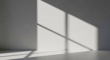 Tek renkli iç mekan, düz zeminde geometrik gölgeler bırakan güçlü pencere ışığına sahiptir..