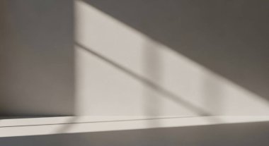 A minimal interior scene with diagonal light and shadows across walls and floor, creating a calm abstract composition of geometric lines.