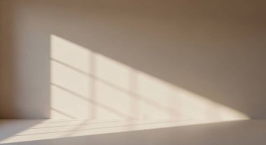 Soft daylight enters an empty room, casting sharp rectangular shadows across the floor and wall, creating a calm minimalist atmosphere.