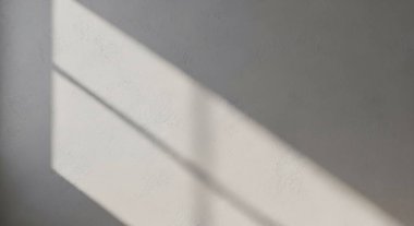 Yumuşak gün ışığı pencerelerden süzülür. Sakin bir iç duvar boyunca çizgili gölgeler yaratır..