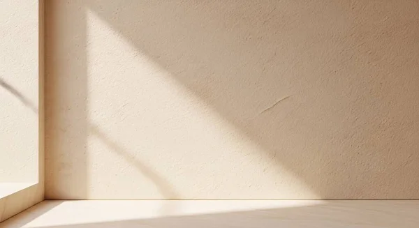 Temiz duvarları ve sıcak köşeli gölgeleri olan güneşli boş bir köşe huzurlu, modern bir alan yaratıyor.